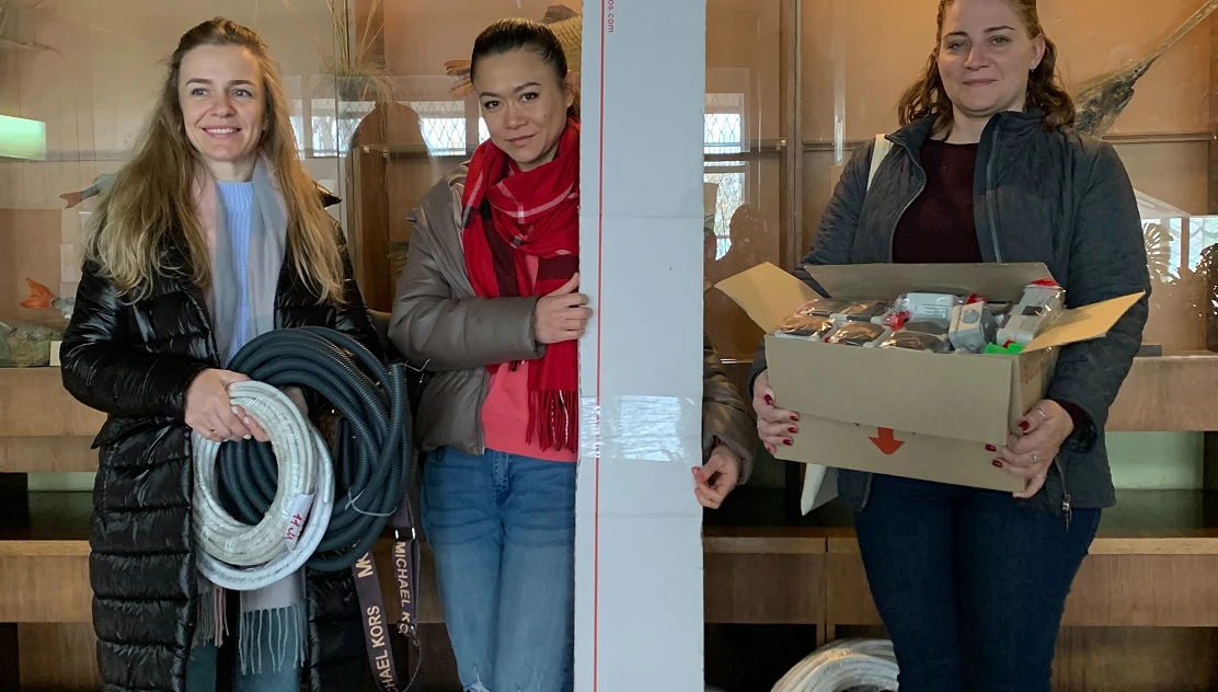 Three volunteers holding donated supplies