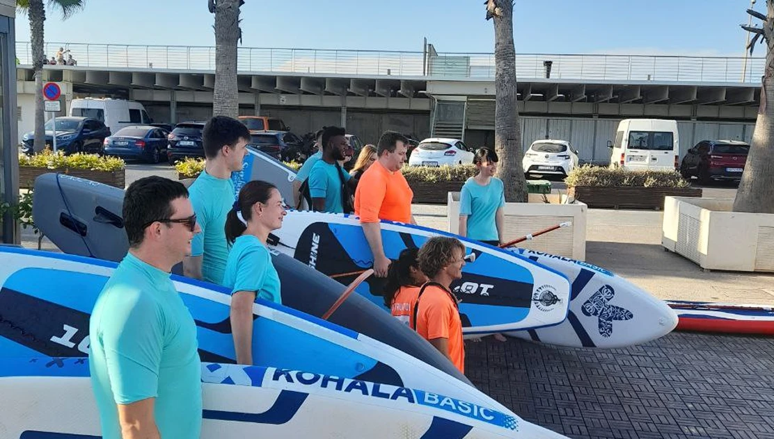 Go Wombat team carrying paddle boards on a team outing