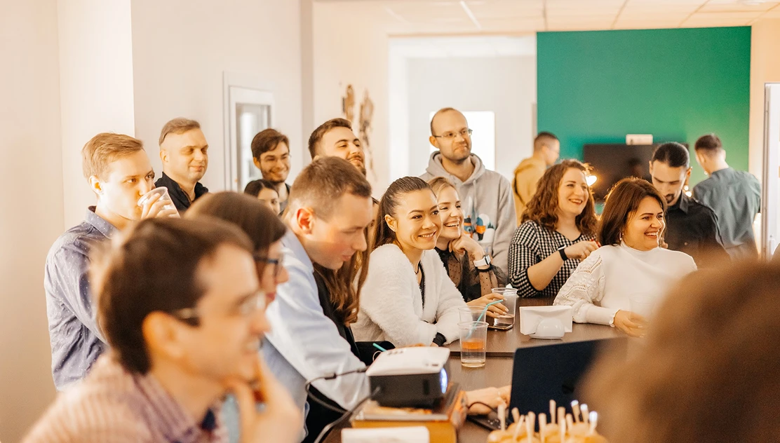 Go Wombat team gathered around a table at an office event